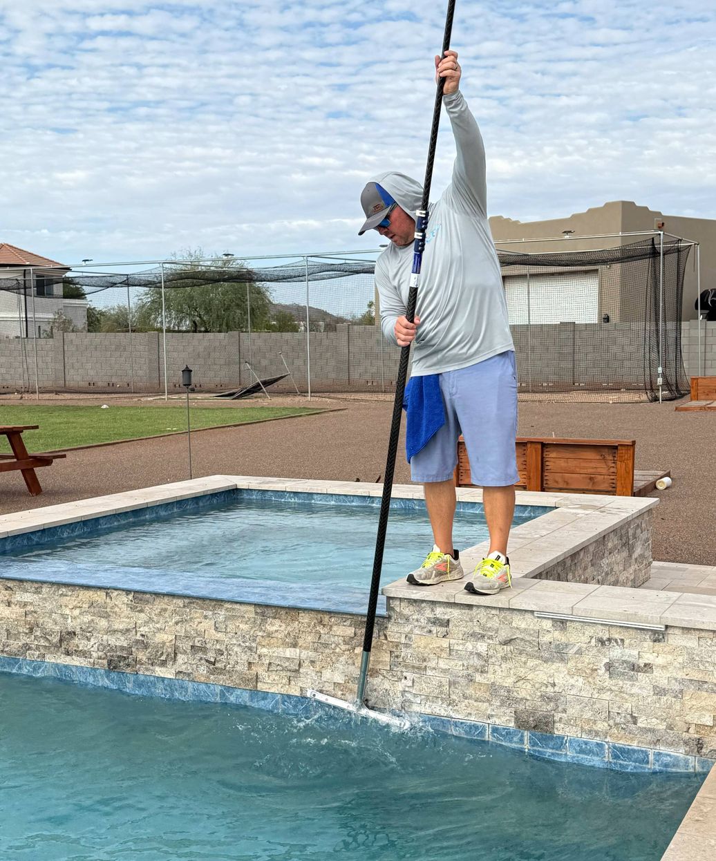 professional pool technician brushing and skimming Phoenix pool